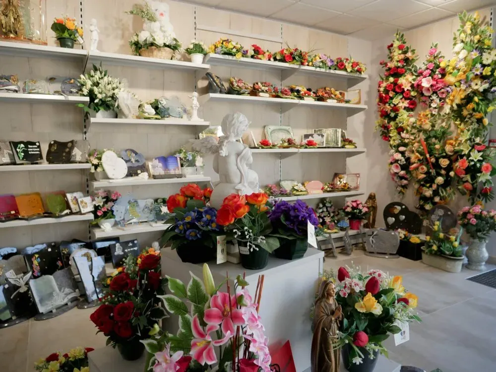 Intérieur du magasin funéraire avec exposition de plaques mémorielles et fleurs.