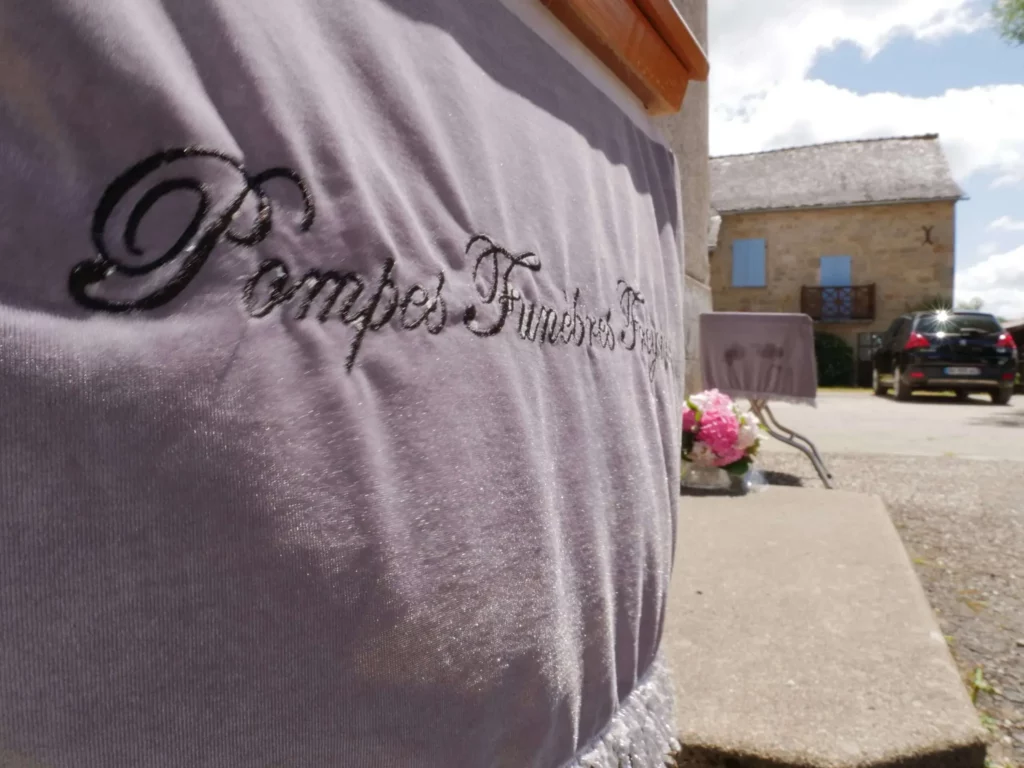 Drap funéraire brodé Pompes Funèbres Freycinet lors d'une cérémonie en extérieur.