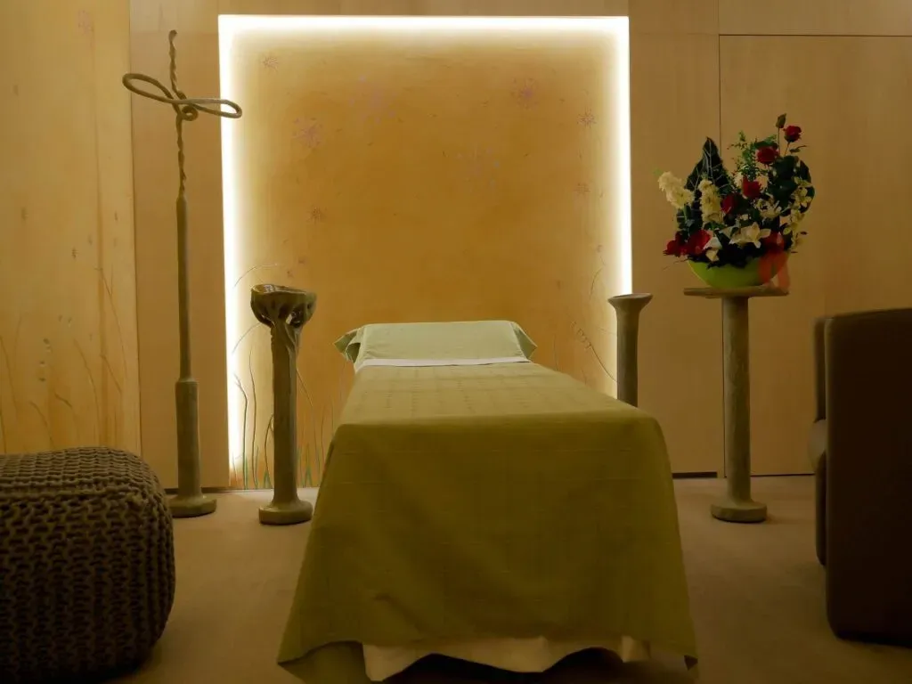 Chambre funéraire apaisante aux tons chauds avec lit de repos et fleurs.